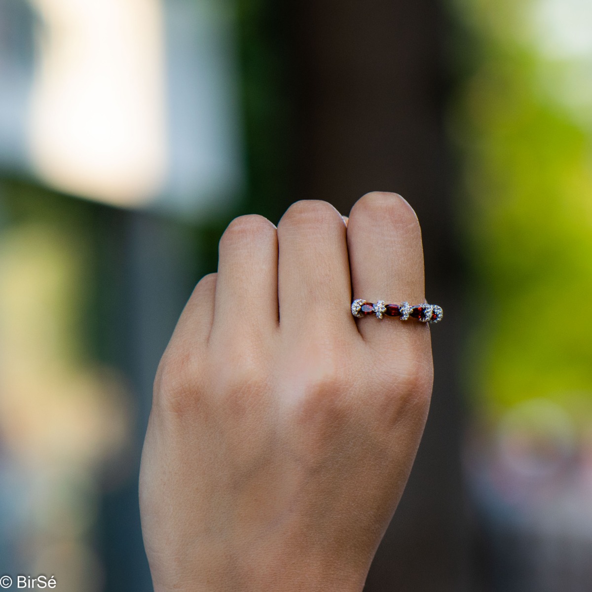 Delicate women's ring intertwining radiant natural garnet with sparkling zircons and exquisite workmanship entirely of rhodium-plated silver.