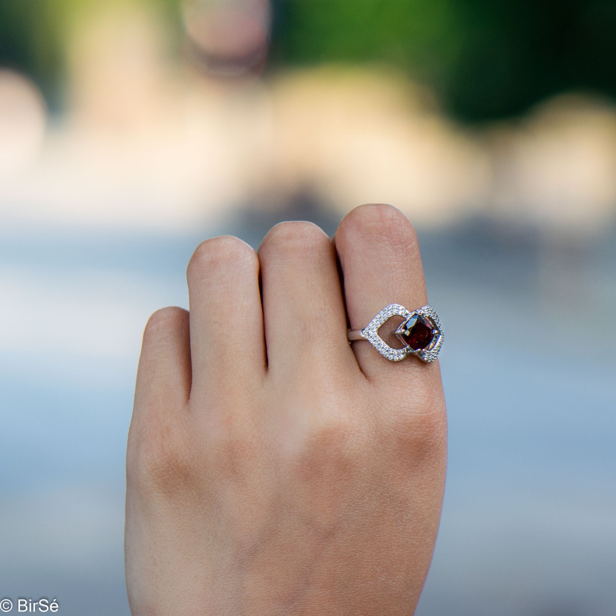 A spectacular women's ring with exquisite workmanship entirely of rhodium-plated silver, combined with a radiant natural garnet stone and sparkling zircons. Can be combined with dangling earrings and a pendant of the same model.