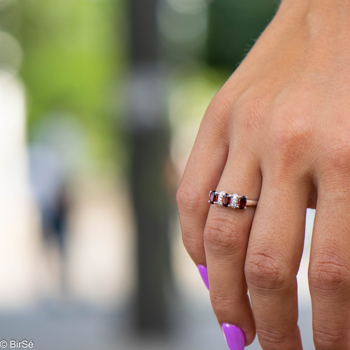 An elegant women's ring with delicate craftsmanship combining rhodium-plated silver with three radiant natural garnet stones and sparkling zircons.