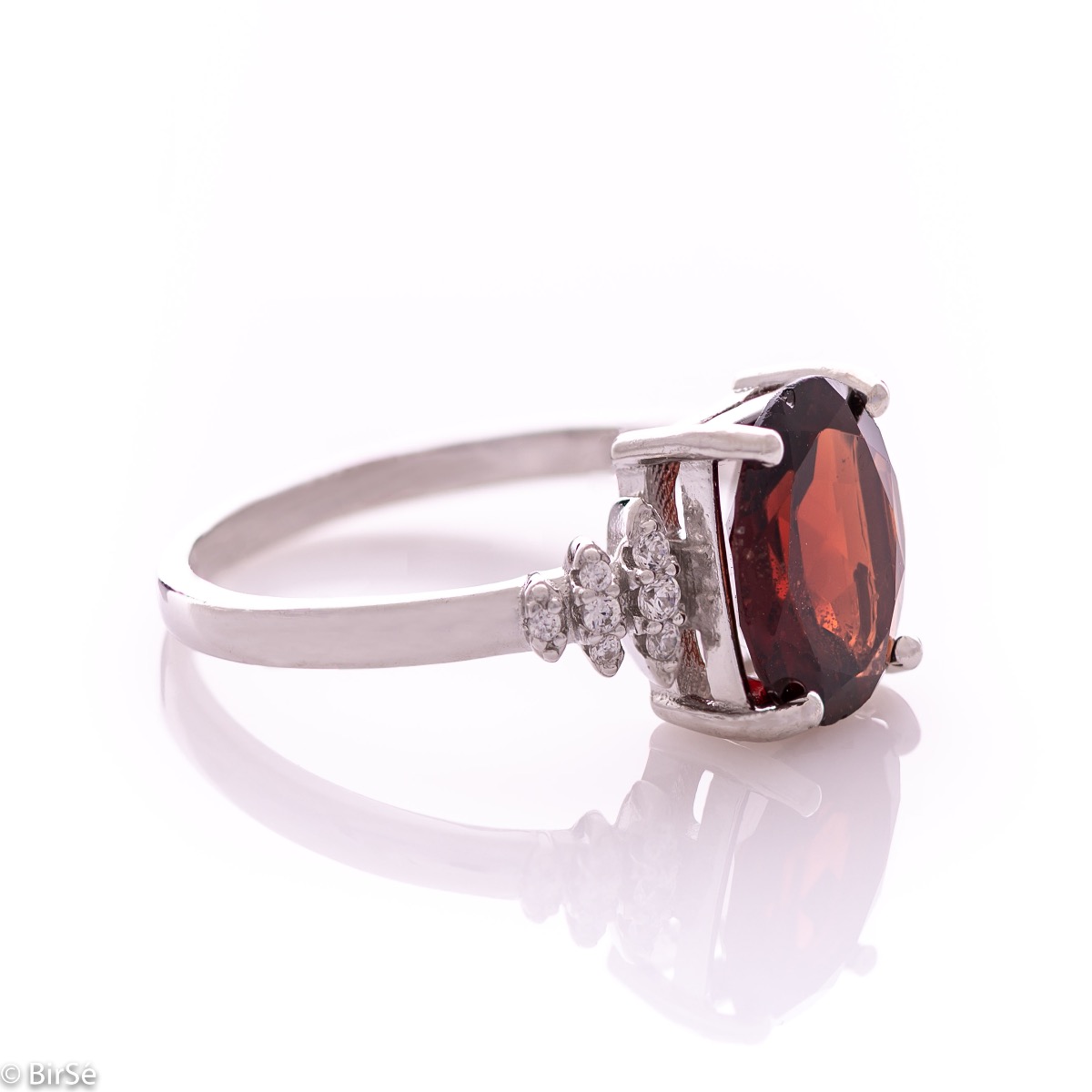 An exquisite women's ring with exceptional workmanship entirely of rhodium-plated silver, combined with a radiant natural garnet and sparkling zircons. Can be combined with earrings and pendant of the same model.