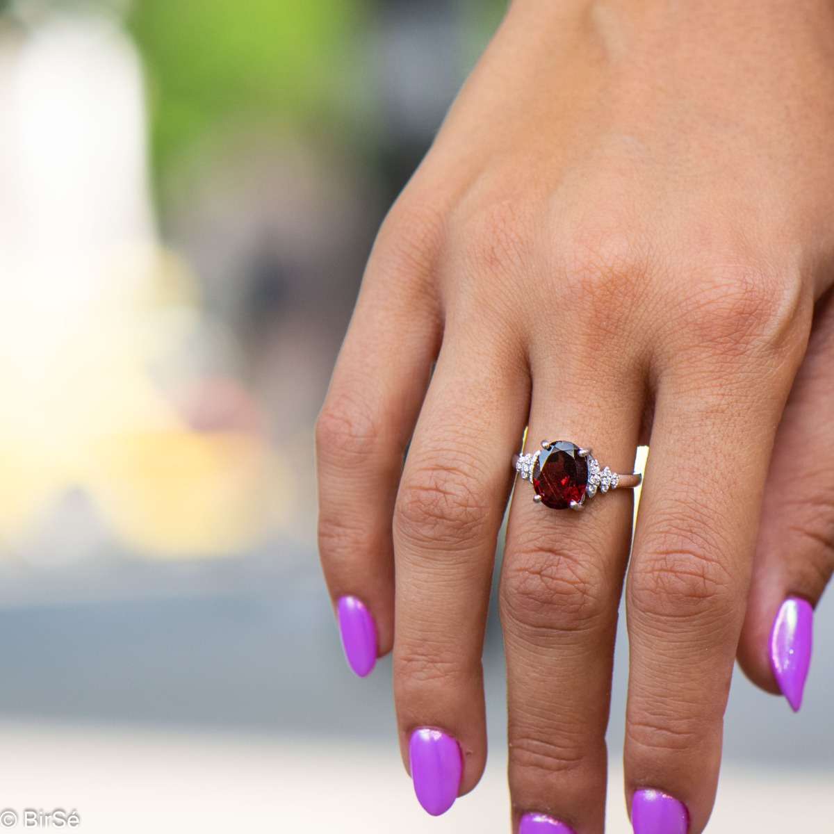 An exquisite women's ring with exceptional workmanship entirely of rhodium-plated silver, combined with a radiant natural garnet and sparkling zircons. Can be combined with earrings and pendant of the same model.