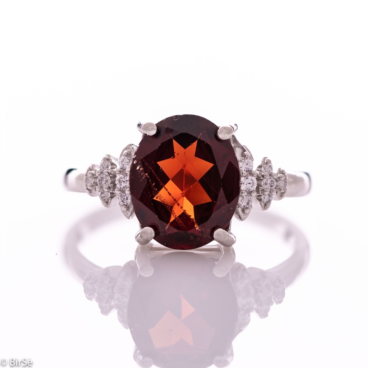 An exquisite women's ring with exceptional workmanship entirely of rhodium-plated silver, combined with a radiant natural garnet and sparkling zircons. Can be combined with earrings and pendant of the same model.