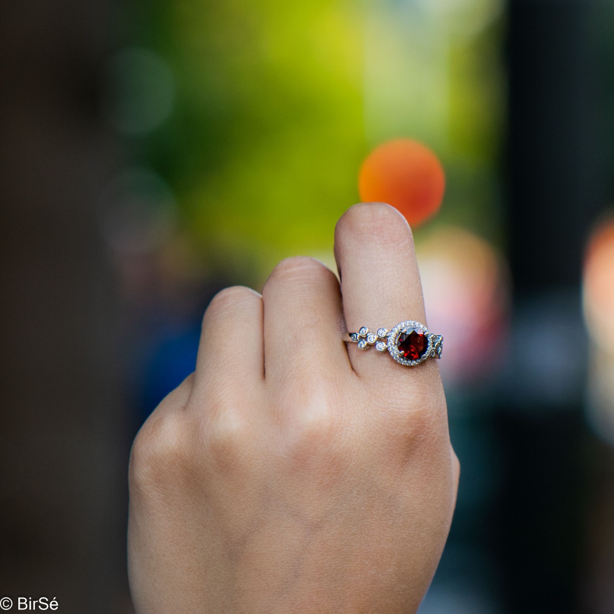 An elegant women's ring with a spectacular workmanship entirely of rhodium-plated silver, combined with a radiant natural garnet and sparkling zircons. Can be combined with earrings and pendant of the same model.