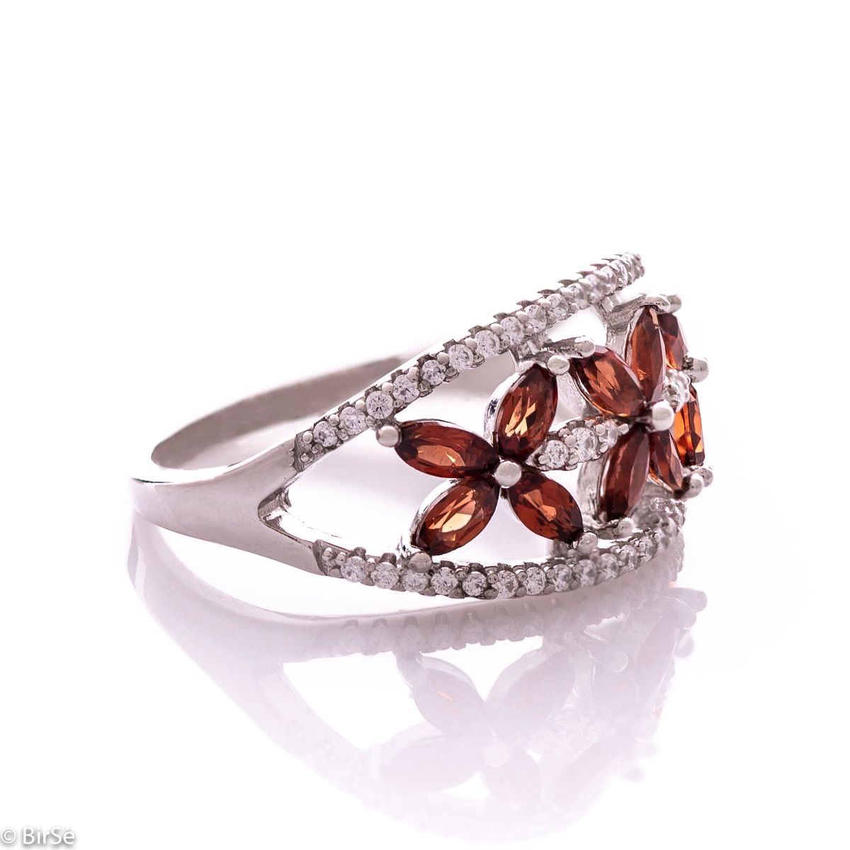 An elegant women's ring with a spectacular design entirely of rhodium-plated silver, combined with delicate flowers of natural garnet and zircons. Can be combined with earrings and pendant of the same model.