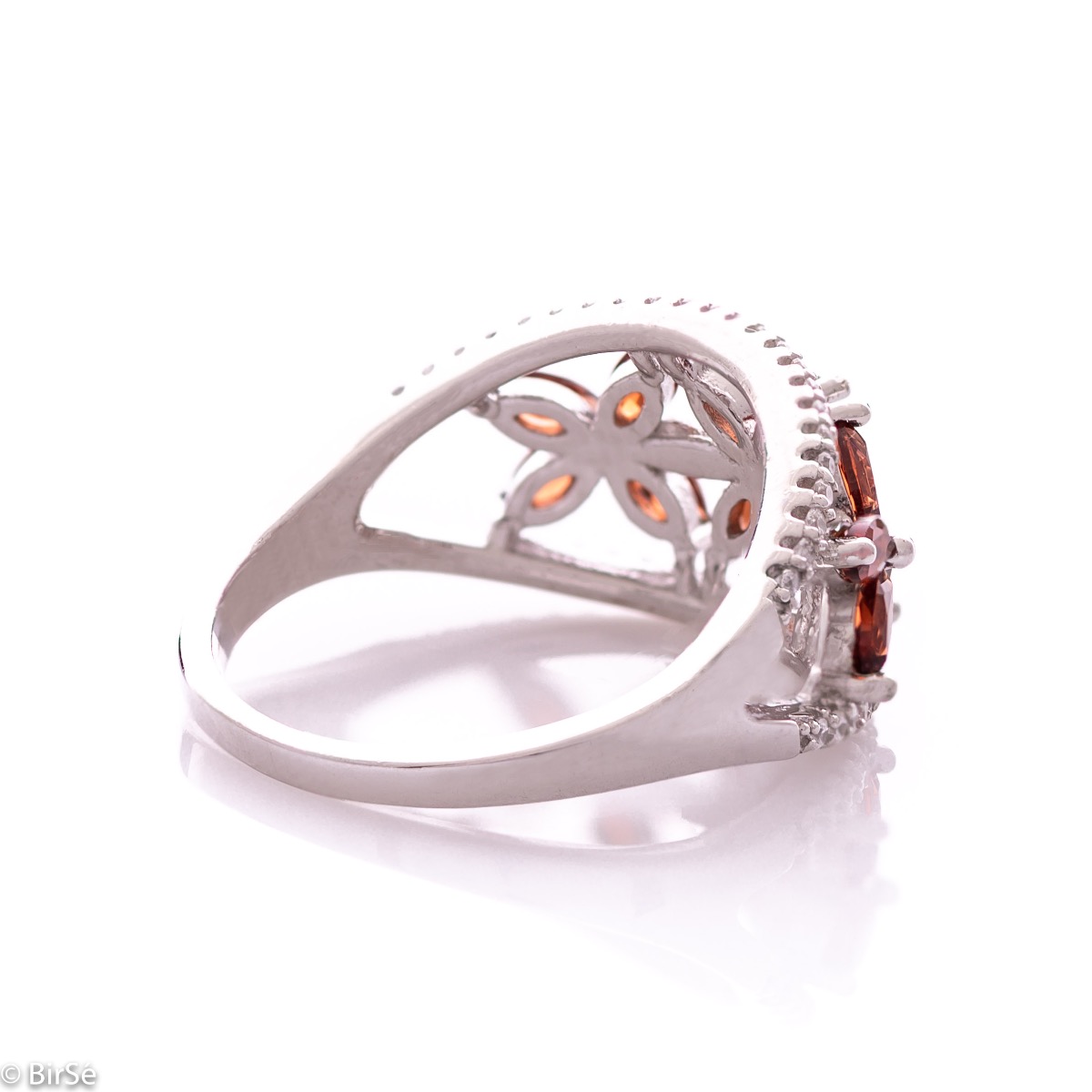 An elegant women's ring with a spectacular design entirely of rhodium-plated silver, combined with delicate flowers of natural garnet and zircons. Can be combined with earrings and pendant of the same model.