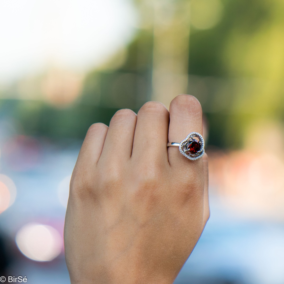 An exquisite women's ring with exceptional workmanship combining a radiant natural garnet with sparkling zircons and delicate rhodium-plated silver.