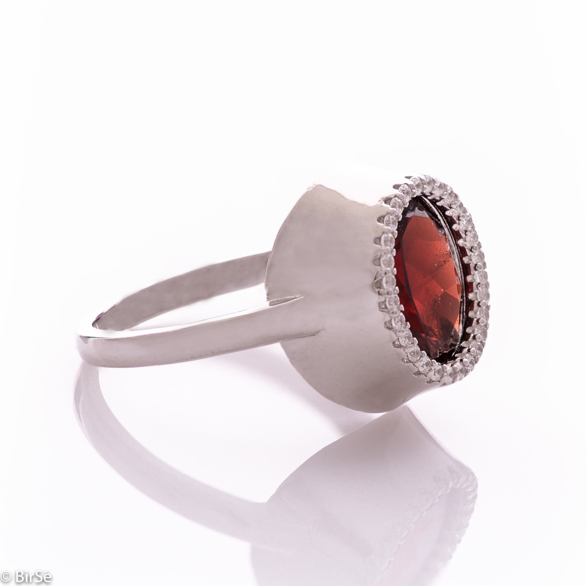 An elegant women's ring with precise craftsmanship combining a radiant natural garnet surrounded by sparkling zircons and delicate rhodium silver. It can be combined with a pendant and earrings of the same model.