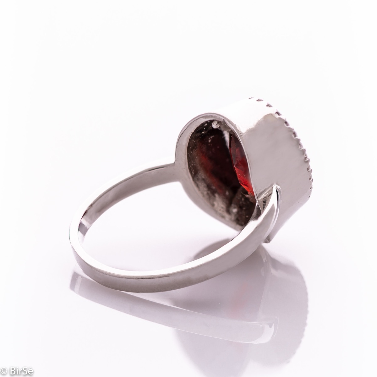 An elegant women's ring with precise craftsmanship combining a radiant natural garnet surrounded by sparkling zircons and delicate rhodium silver. It can be combined with a pendant and earrings of the same model.