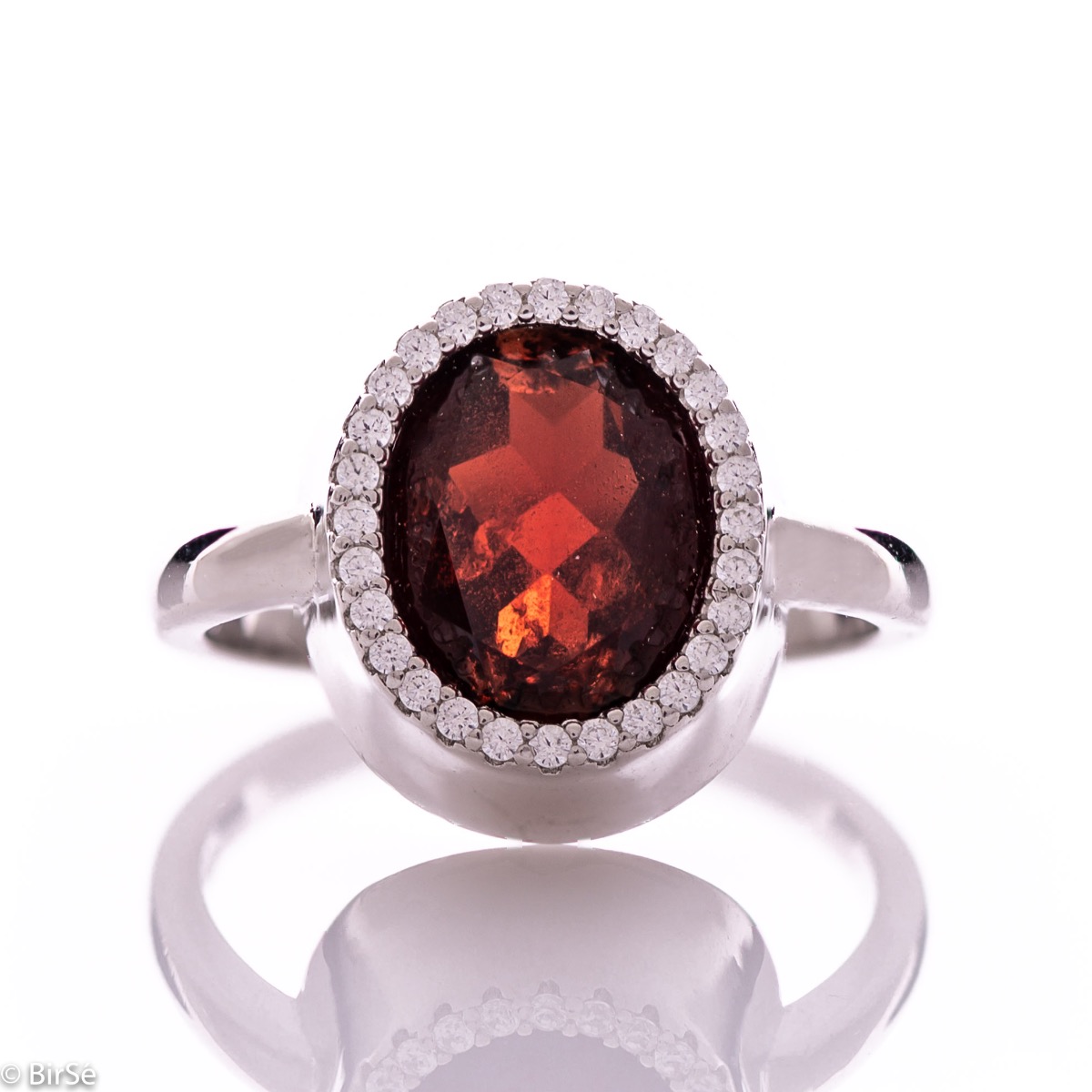 An elegant women's ring with precise craftsmanship combining a radiant natural garnet surrounded by sparkling zircons and delicate rhodium silver. It can be combined with a pendant and earrings of the same model.