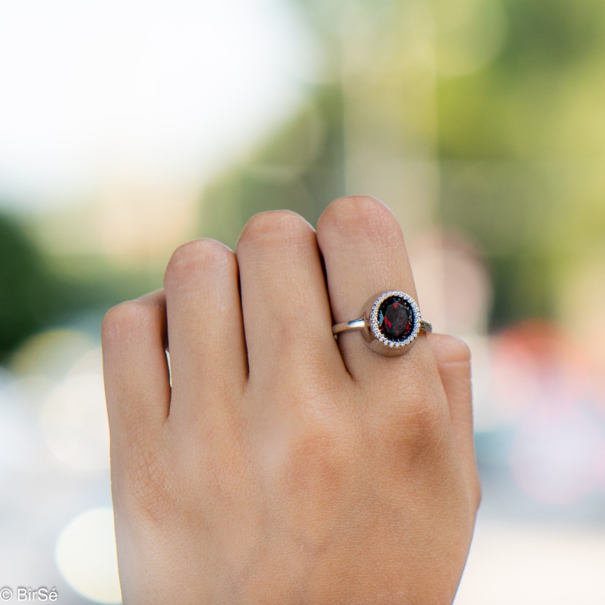 An elegant women's ring with precise craftsmanship combining a radiant natural garnet surrounded by sparkling zircons and delicate rhodium silver. It can be combined with a pendant and earrings of the same model.