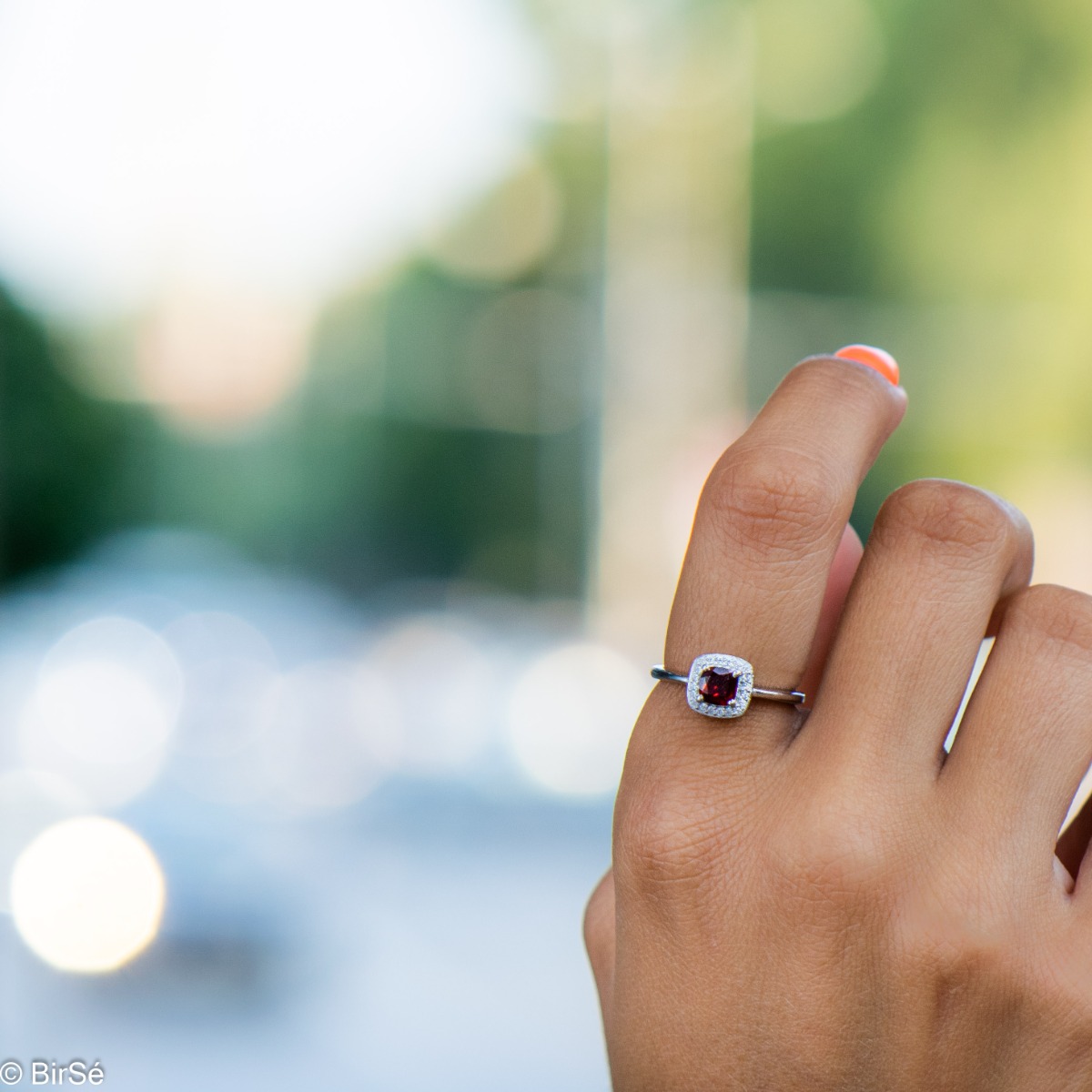 An exquisitely crafted ring of brilliant rhodium-plated silver with interestingly shaped details. A central role is occupied by a magnetic natural garnet, beautifully surrounded by small fine zircons. Can be combined with earrings and pendant from the set