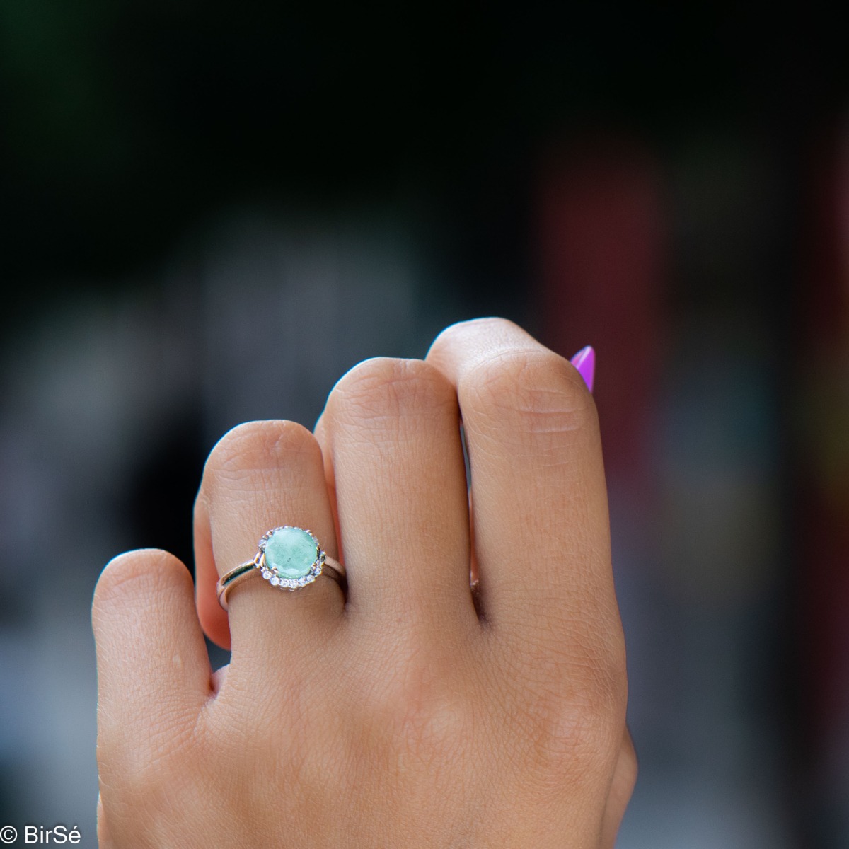 Delicately elegant silver ring with a spectacular look and modern design. Stylishly crafted from a fine combination of rhodium-plated silver with a natural emerald and a halo of sparkling zircons. Part of a fine English clasp pendant and earring set.