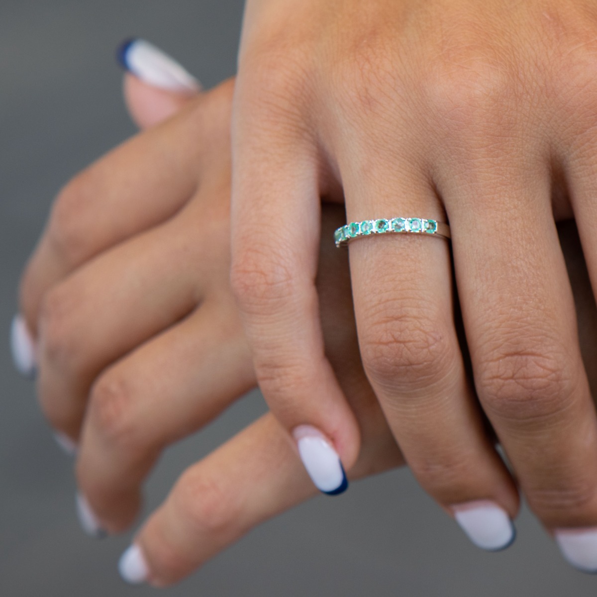 Finely crafted fine rhodium silver women's ring with a row of charming natural emeralds.