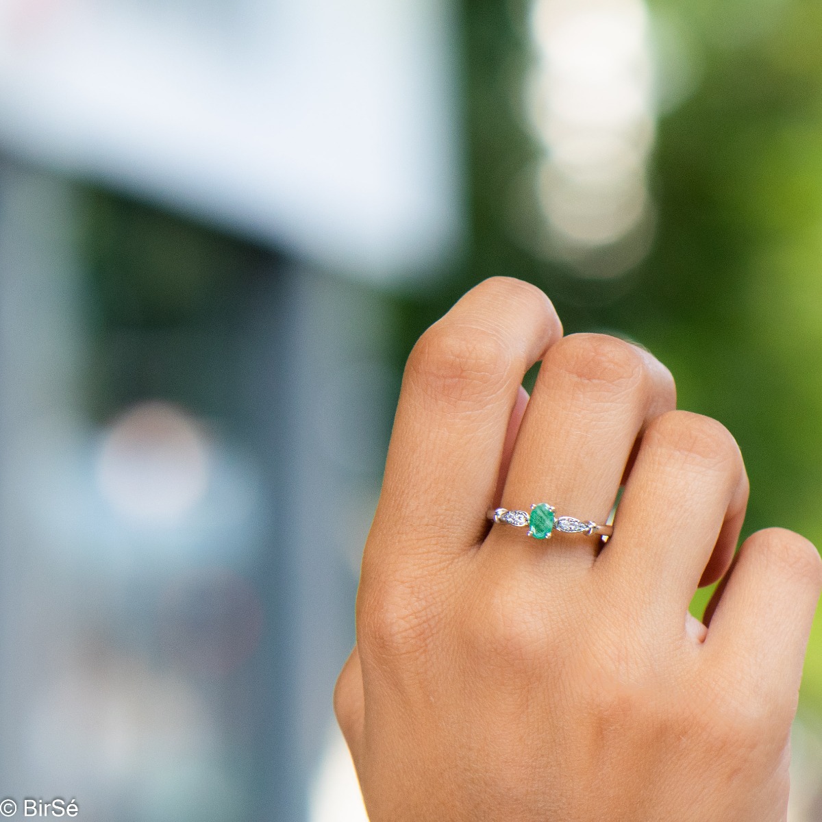 An elegant women's ring with a modern design of the detail and extraordinary craftsmanship entirely of rhodium-plated silver, complemented by the glow of natural emerald stone and fine zircons. In an exclusive sterling silver set with earrings and pendant