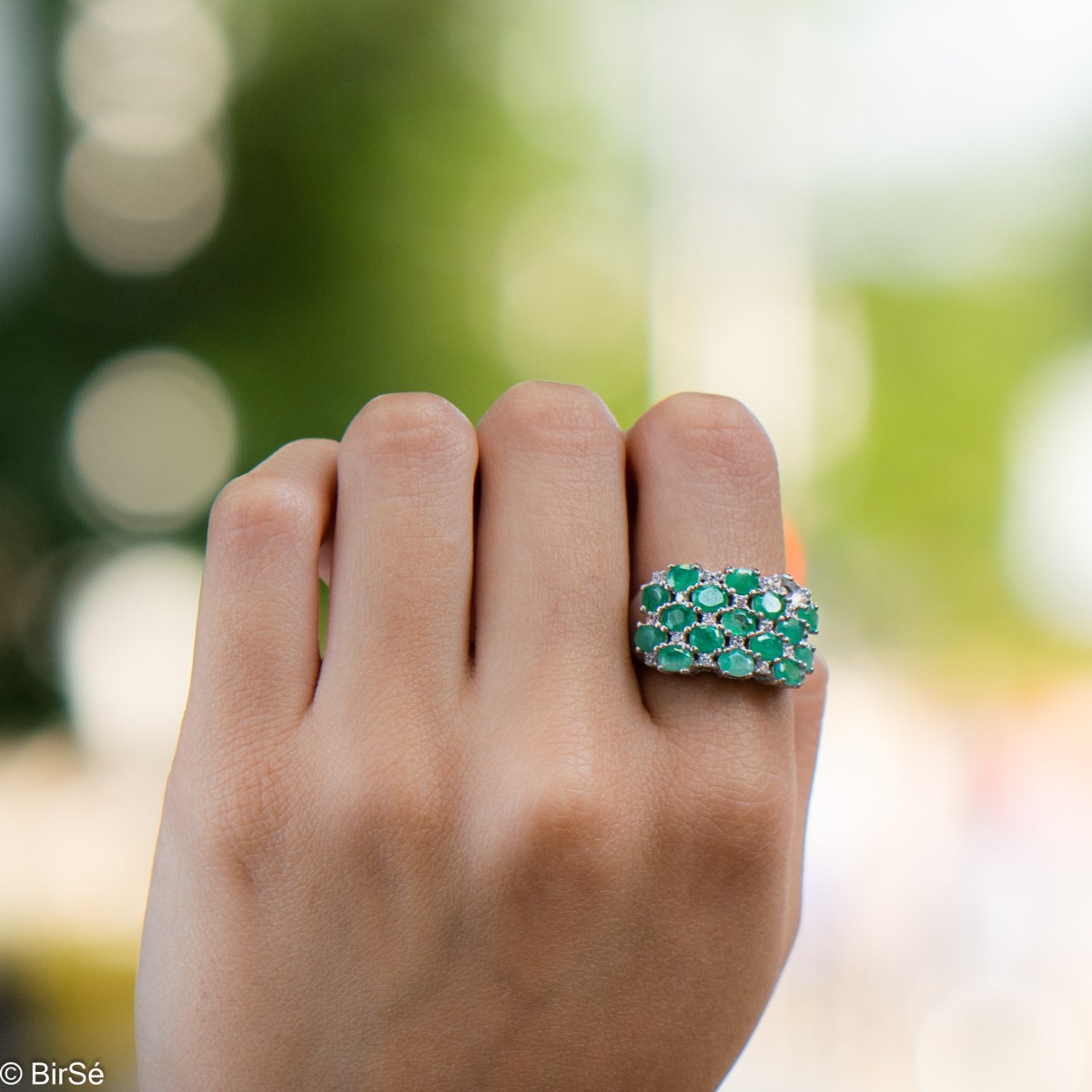 Women's ring with modern craftsmanship, combining numerous fine natural emerald stones, complemented by the sparkle of zircons and made entirely of rhodium-plated silver. In a charming set with matching necklace and earrings.