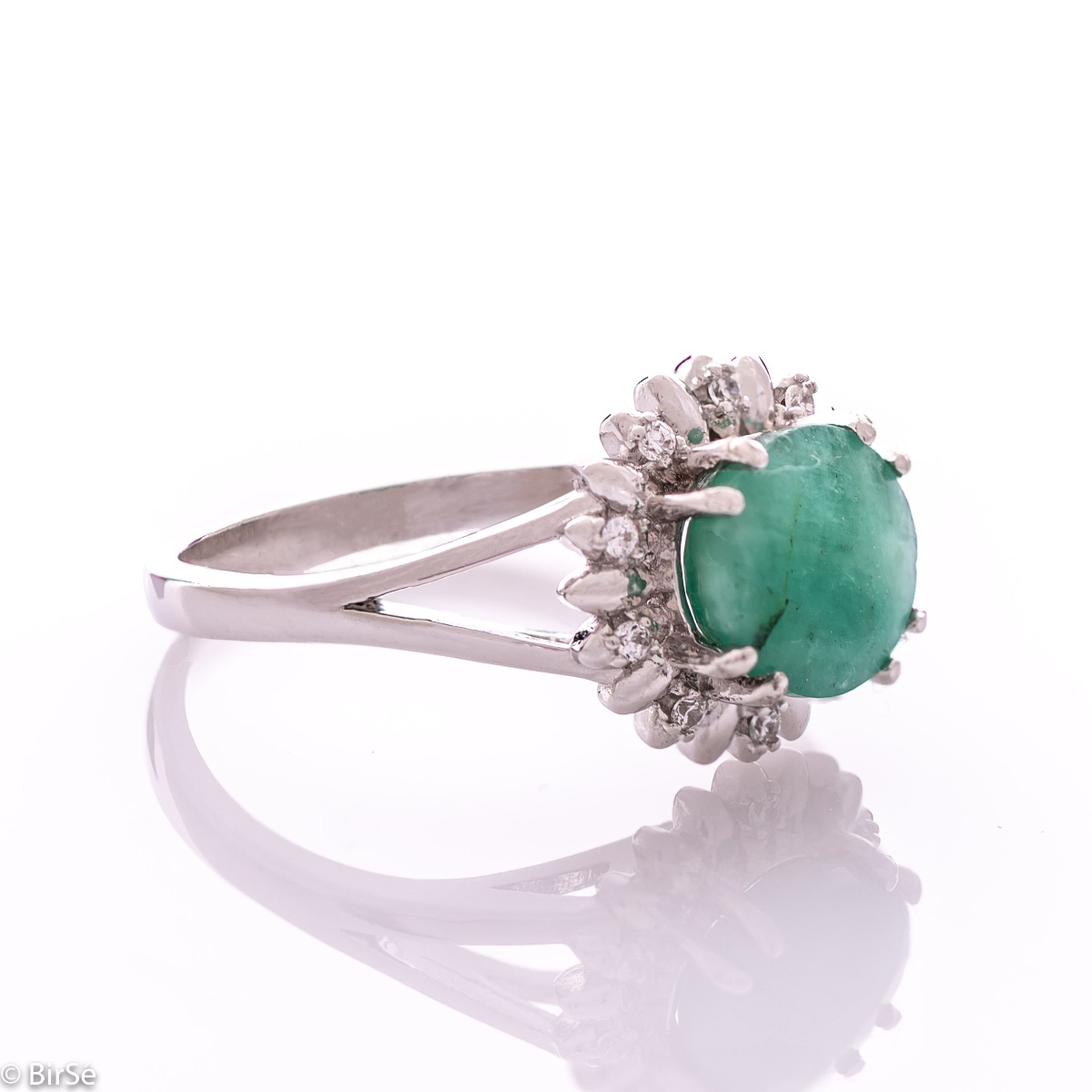 An elegant women's ring with precise craftsmanship combining delicate rhodium-plated silver with a radiant natural emerald surrounded by sparkling zircons. Can be combined with earrings and pendant of the same model.