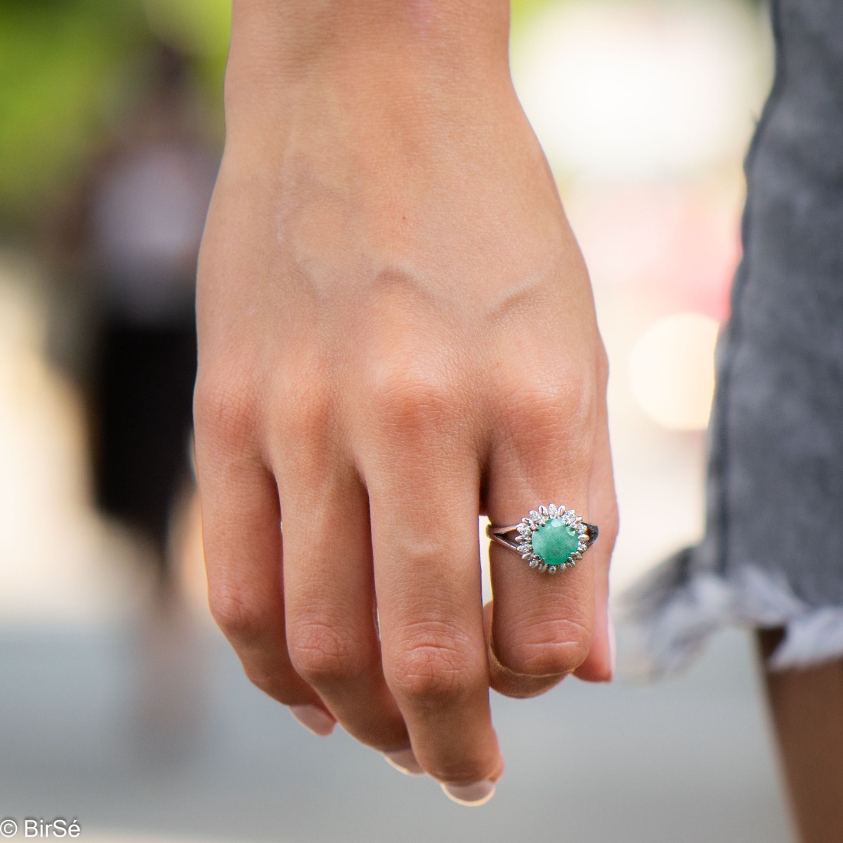 An elegant women's ring with precise craftsmanship combining delicate rhodium-plated silver with a radiant natural emerald surrounded by sparkling zircons. Can be combined with earrings and pendant of the same model.