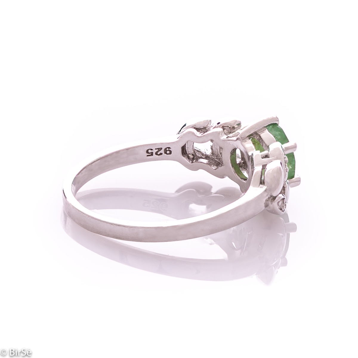 An elegant women's ring with delicate craftsmanship combining refined rhodium-plated silver with a radiant natural emerald and petals of sparkling zircons. Can be combined with earrings and pendant of the same model.