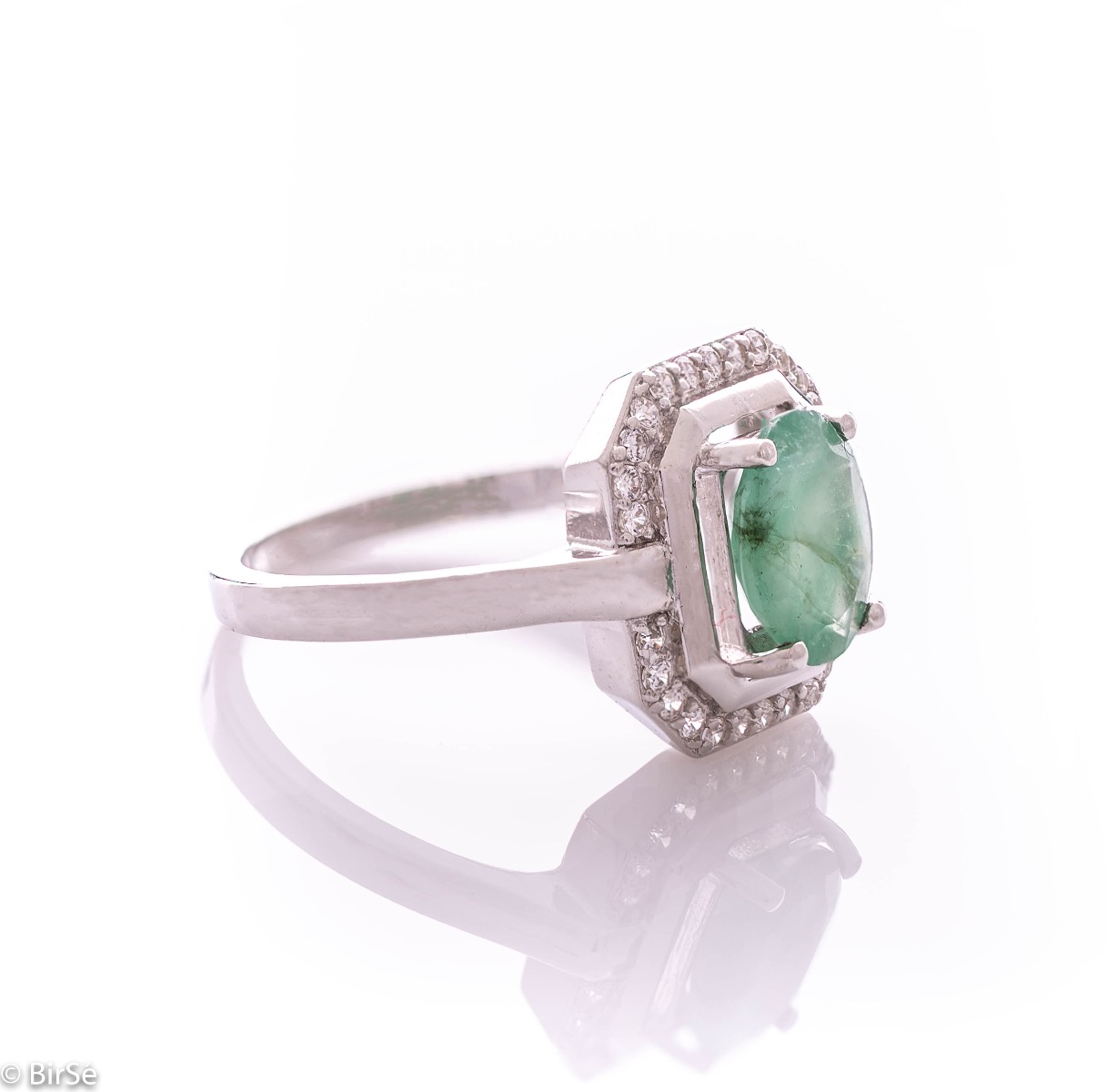 An elegant lady's ring made of rhodium-plated silver, combined with the gentle glow of a natural emerald stone, surrounded by sparkling zircons. It can be combined with a pendant and earrings of the same model.