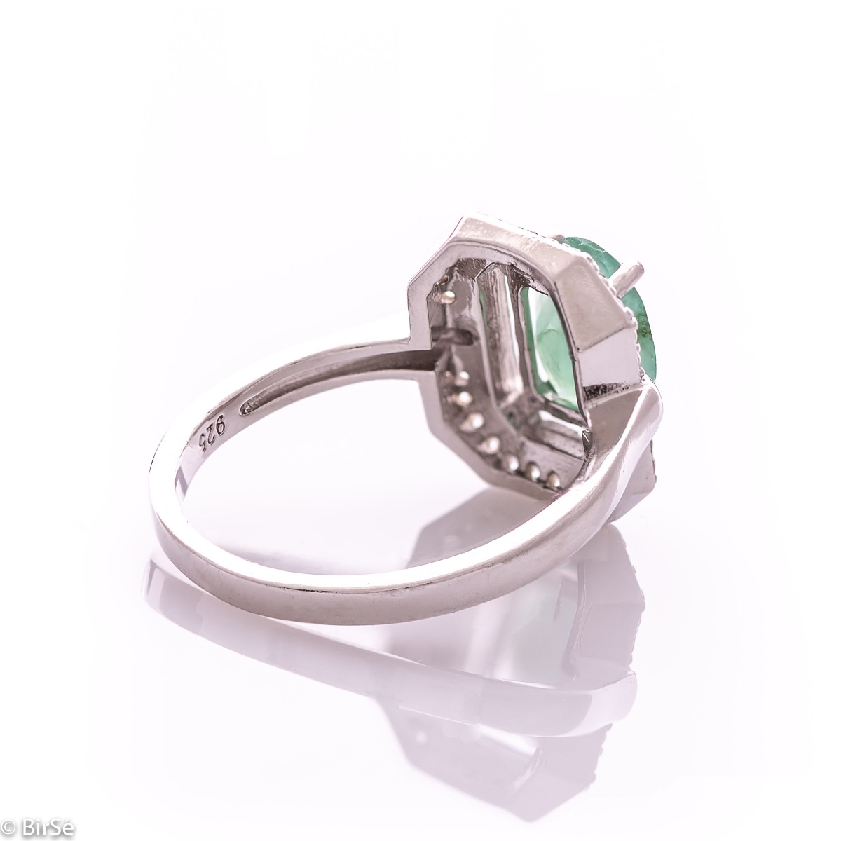 An elegant lady's ring made of rhodium-plated silver, combined with the gentle glow of a natural emerald stone, surrounded by sparkling zircons. It can be combined with a pendant and earrings of the same model.