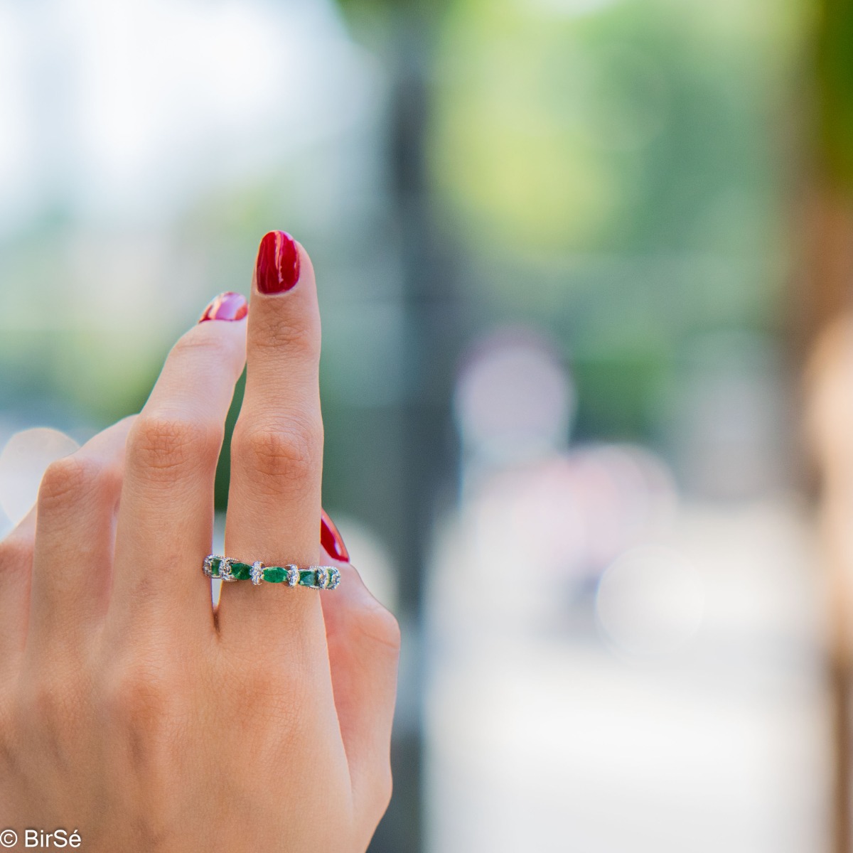 Delicate women's ring intertwining a radiant natural emerald with sparkling zircons and exquisite workmanship entirely in rhodium-plated silver.