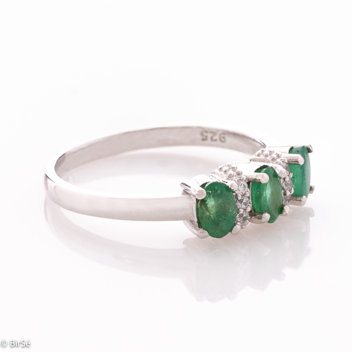 An elegant women's ring with delicate craftsmanship combining rhodium-plated silver with three brilliant natural emerald stones and sparkling zircons.