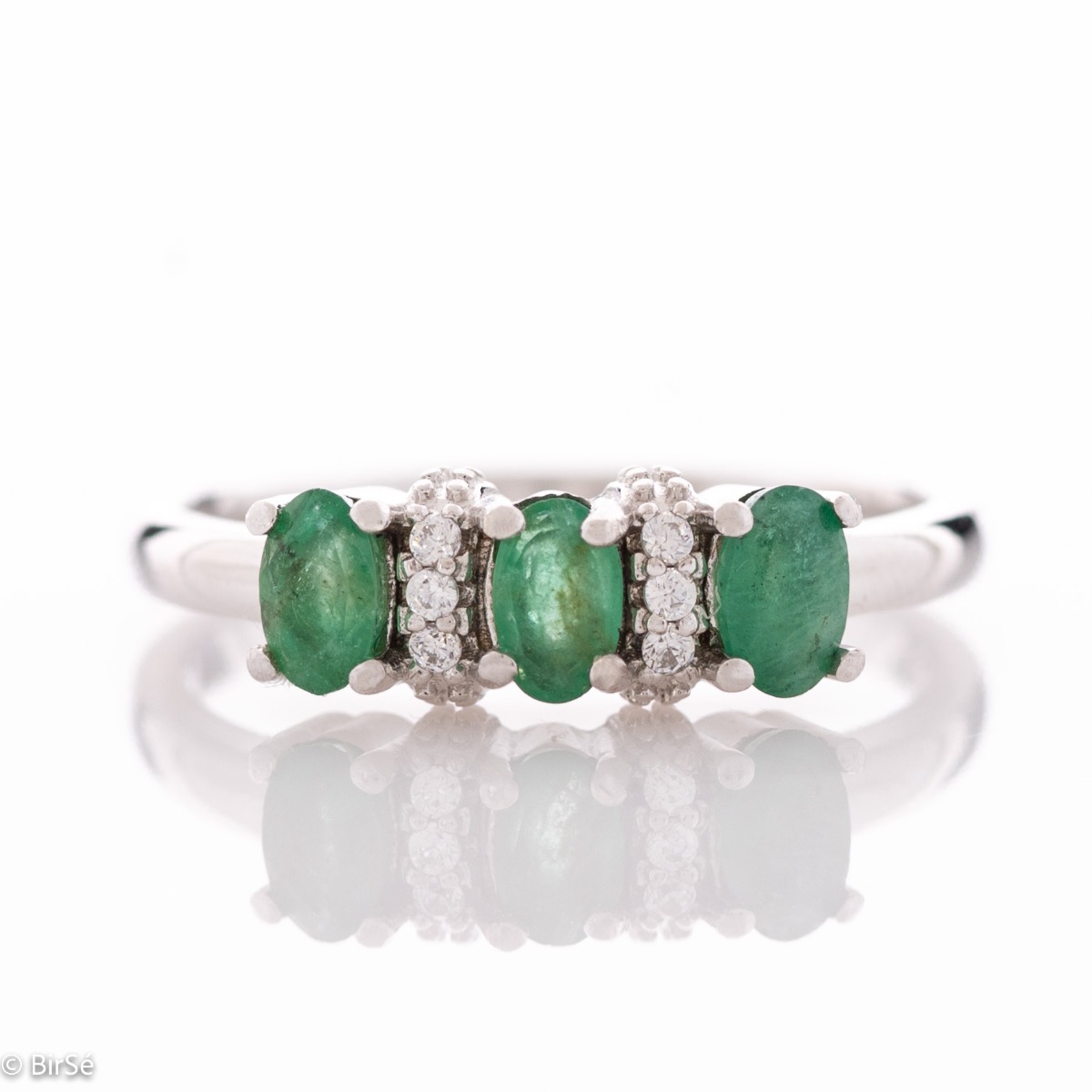 An elegant women's ring with delicate craftsmanship combining rhodium-plated silver with three brilliant natural emerald stones and sparkling zircons.