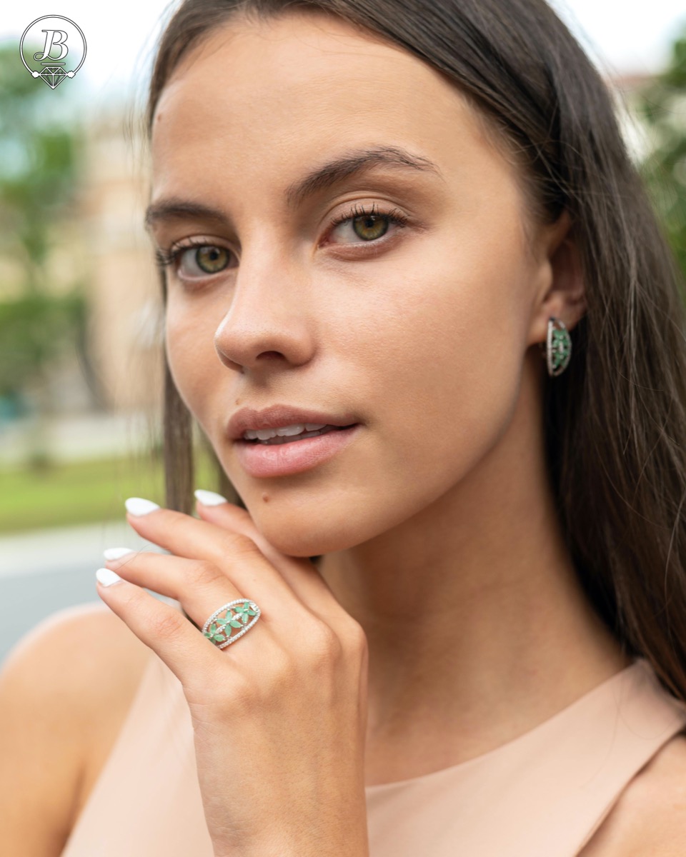 An elegant women's ring with a spectacular workmanship entirely of rhodium-plated silver, combined with delicate flowers of natural emerald and zircons. Can be combined with earrings and pendant of the same model.