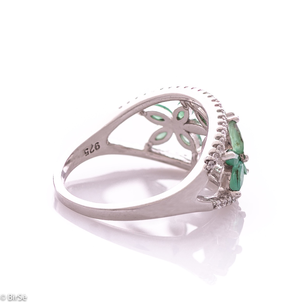 An elegant women's ring with a spectacular workmanship entirely of rhodium-plated silver, combined with delicate flowers of natural emerald and zircons. Can be combined with earrings and pendant of the same model.