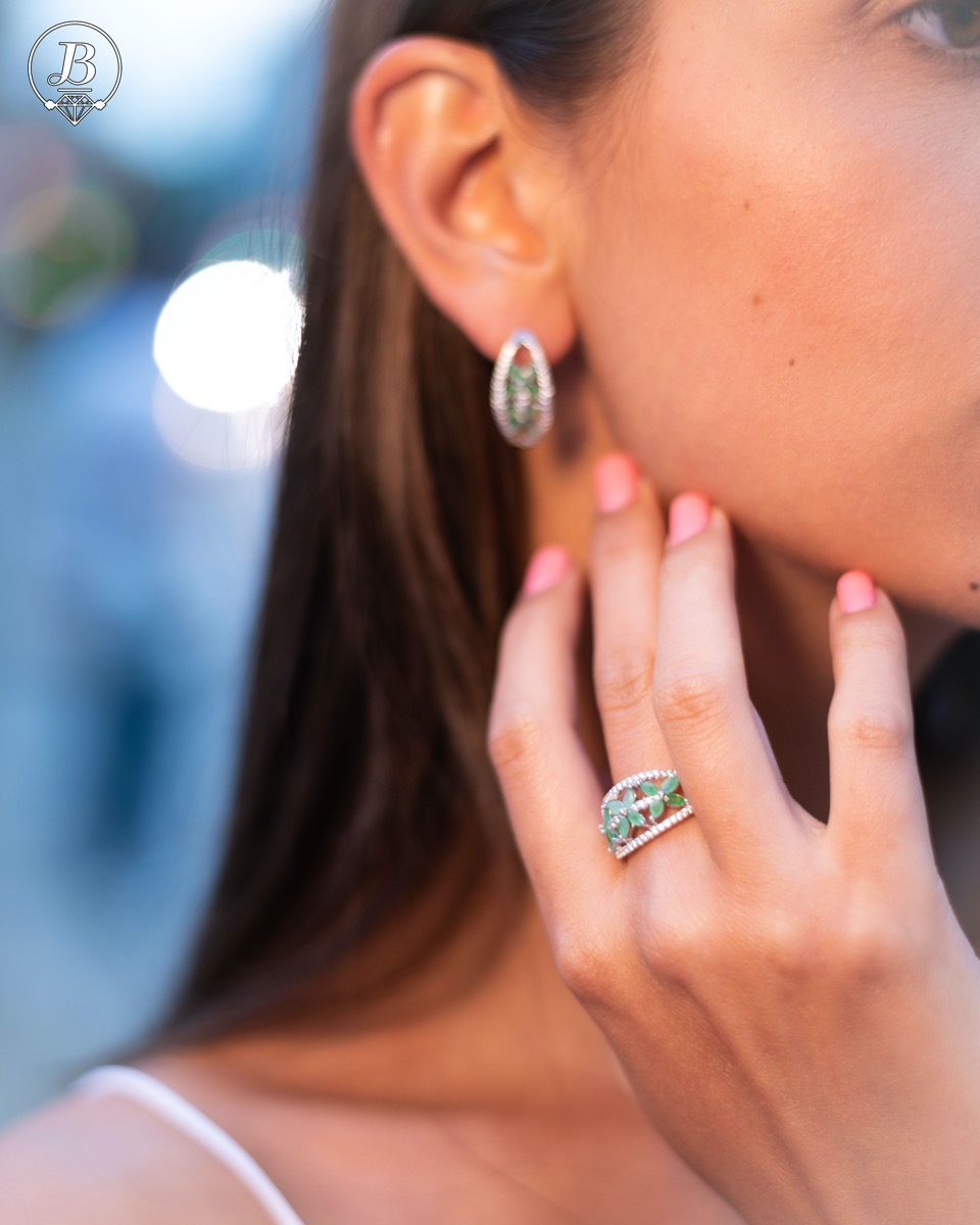 An elegant women's ring with a spectacular workmanship entirely of rhodium-plated silver, combined with delicate flowers of natural emerald and zircons. Can be combined with earrings and pendant of the same model.