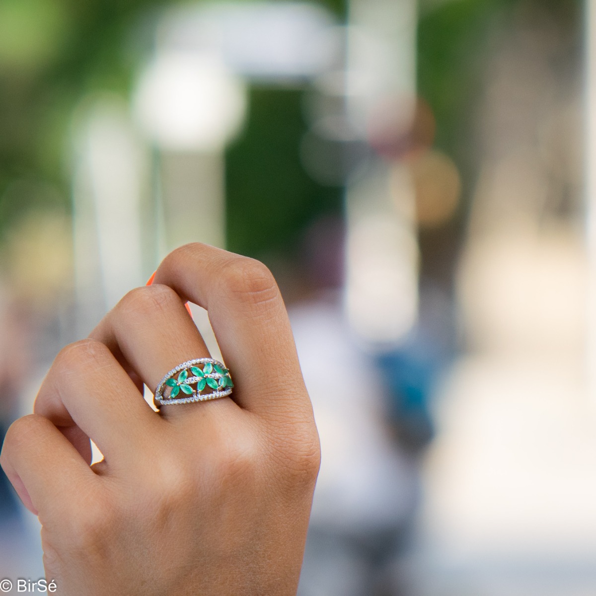 An elegant women's ring with a spectacular workmanship entirely of rhodium-plated silver, combined with delicate flowers of natural emerald and zircons. Can be combined with earrings and pendant of the same model.