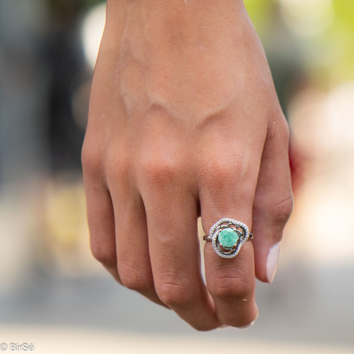 An exquisite women's ring with exceptional workmanship combining a radiant natural emerald with sparkling zircons and delicate rhodium silver. Can be combined with earrings and pendant of the same model.