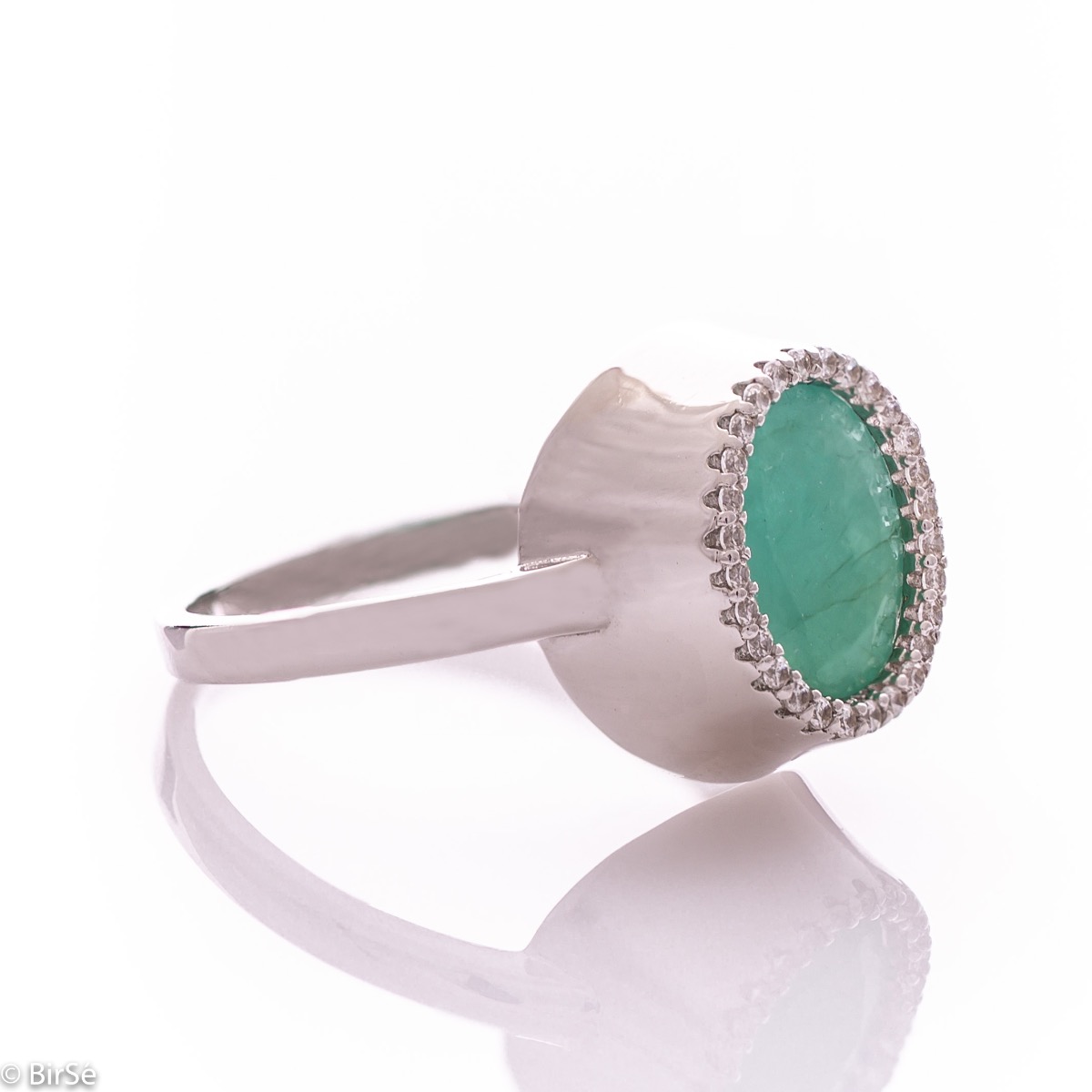 An elegant women's ring with precise craftsmanship combining a radiant natural emerald surrounded by sparkling zircons and delicate rhodium silver. It can be combined with a pendant and earrings of the same model.