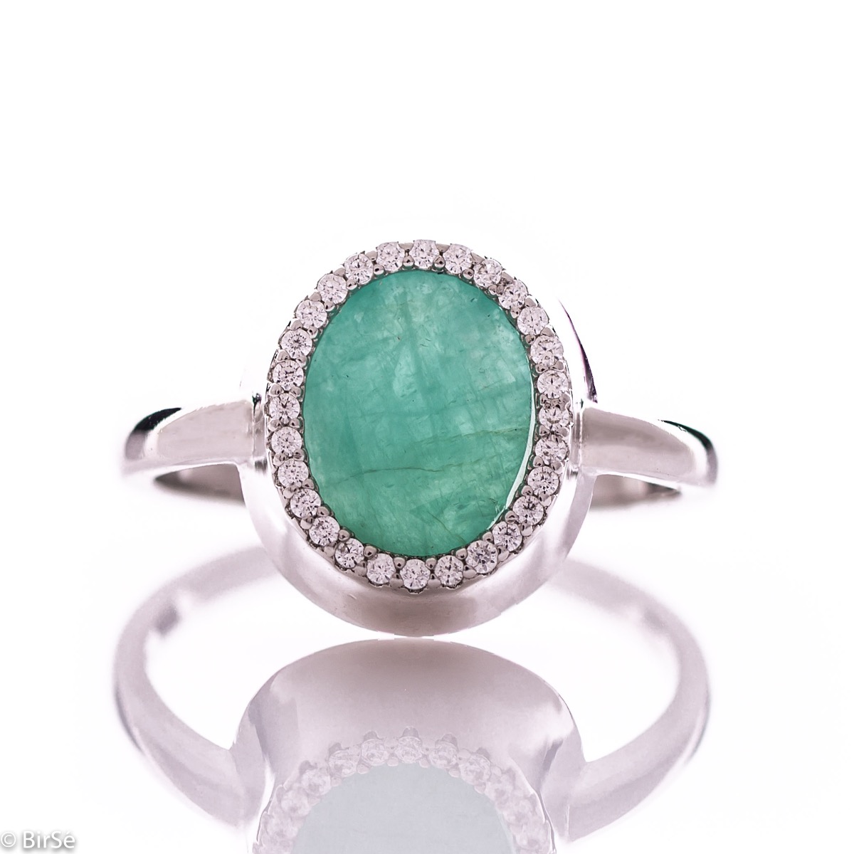 An elegant women's ring with precise craftsmanship combining a radiant natural emerald surrounded by sparkling zircons and delicate rhodium silver. It can be combined with a pendant and earrings of the same model.