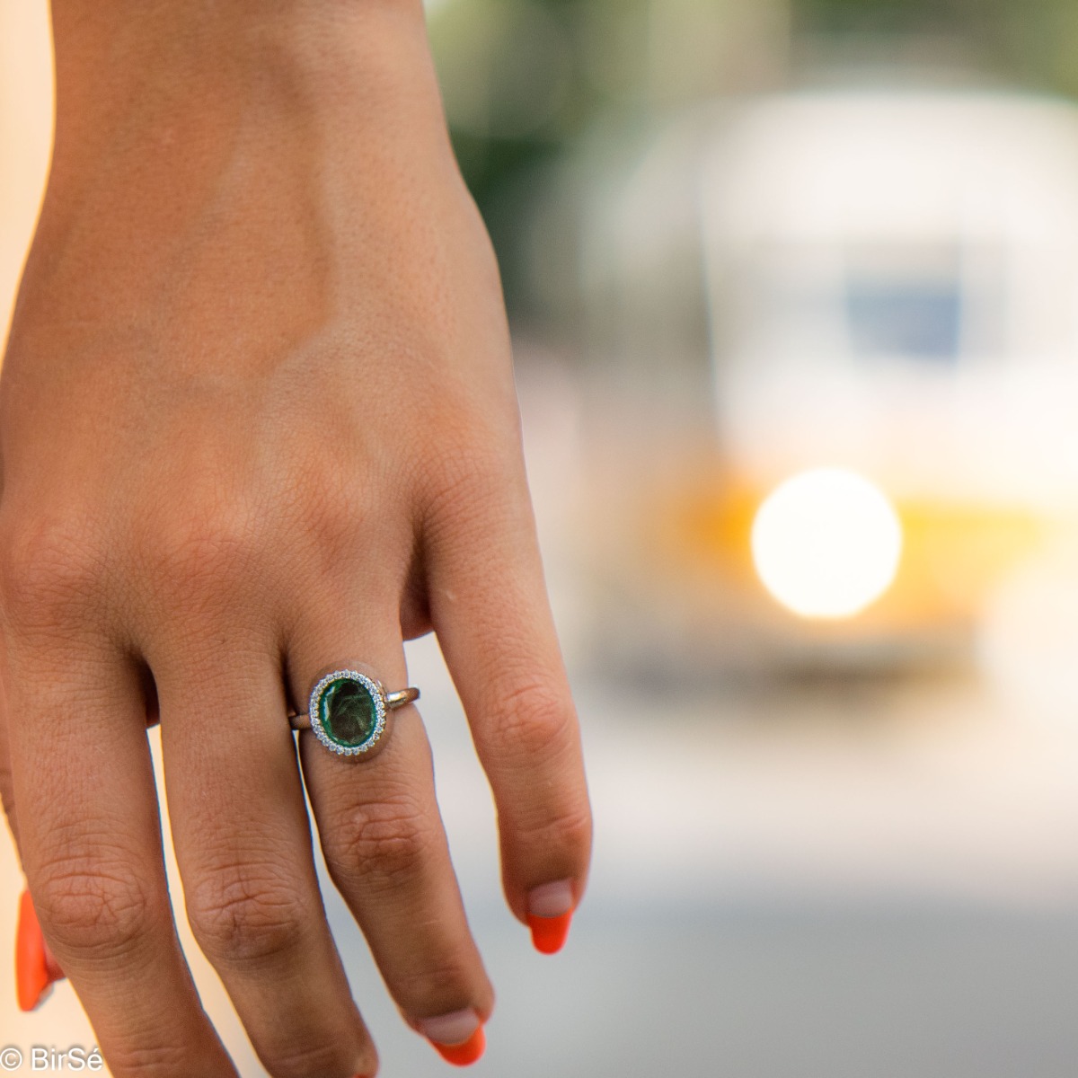 An elegant women's ring with precise craftsmanship combining a radiant natural emerald surrounded by sparkling zircons and delicate rhodium silver. It can be combined with a pendant and earrings of the same model.