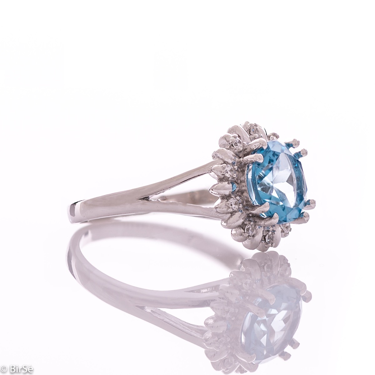 An exquisite women's ring with precise craftsmanship combining delicate rhodium silver with a radiant natural London topaz surrounded by sparkling zircons. Can be combined with earrings and pendant of the same model.