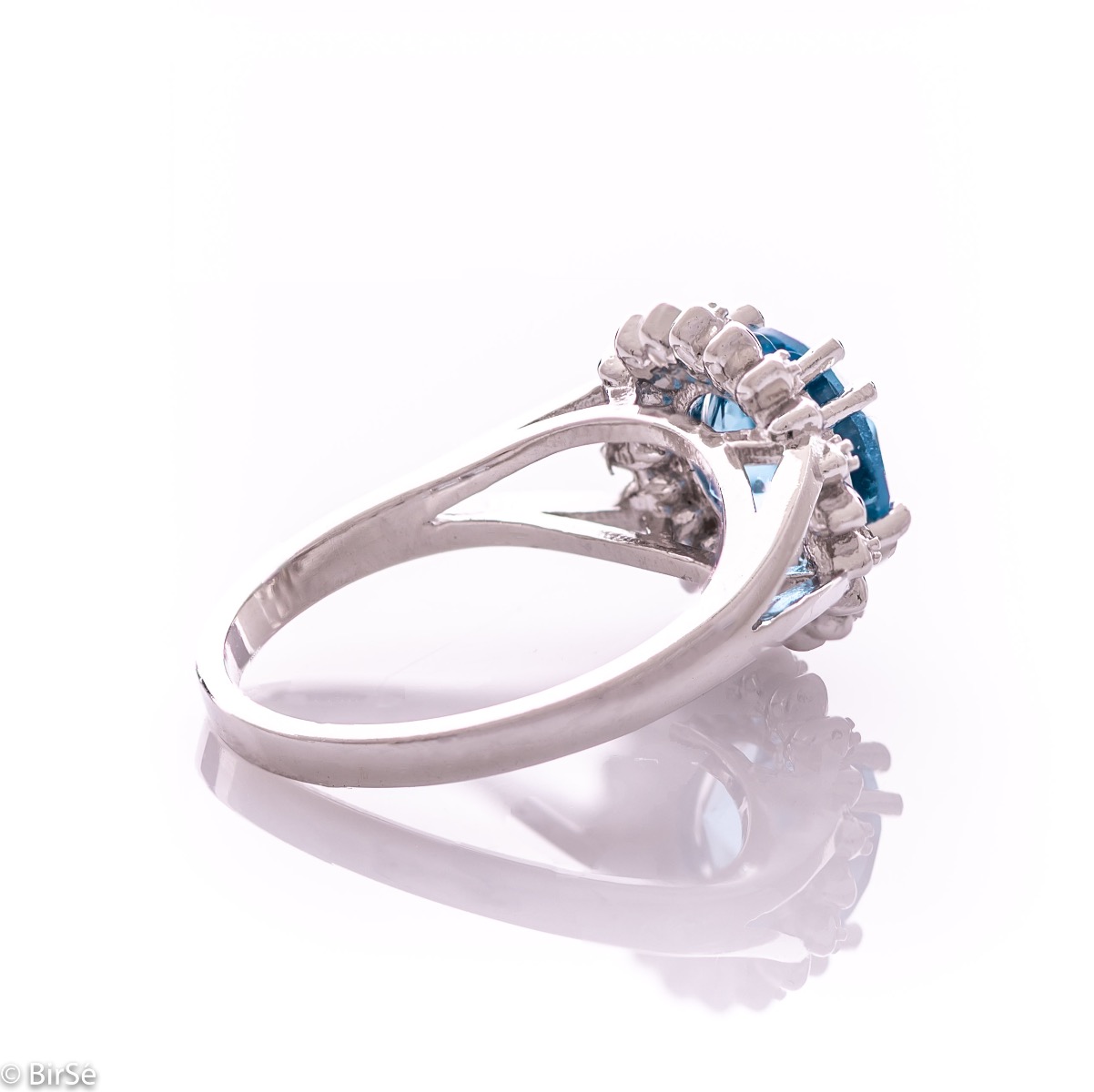 An exquisite women's ring with precise craftsmanship combining delicate rhodium silver with a radiant natural London topaz surrounded by sparkling zircons. Can be combined with earrings and pendant of the same model.