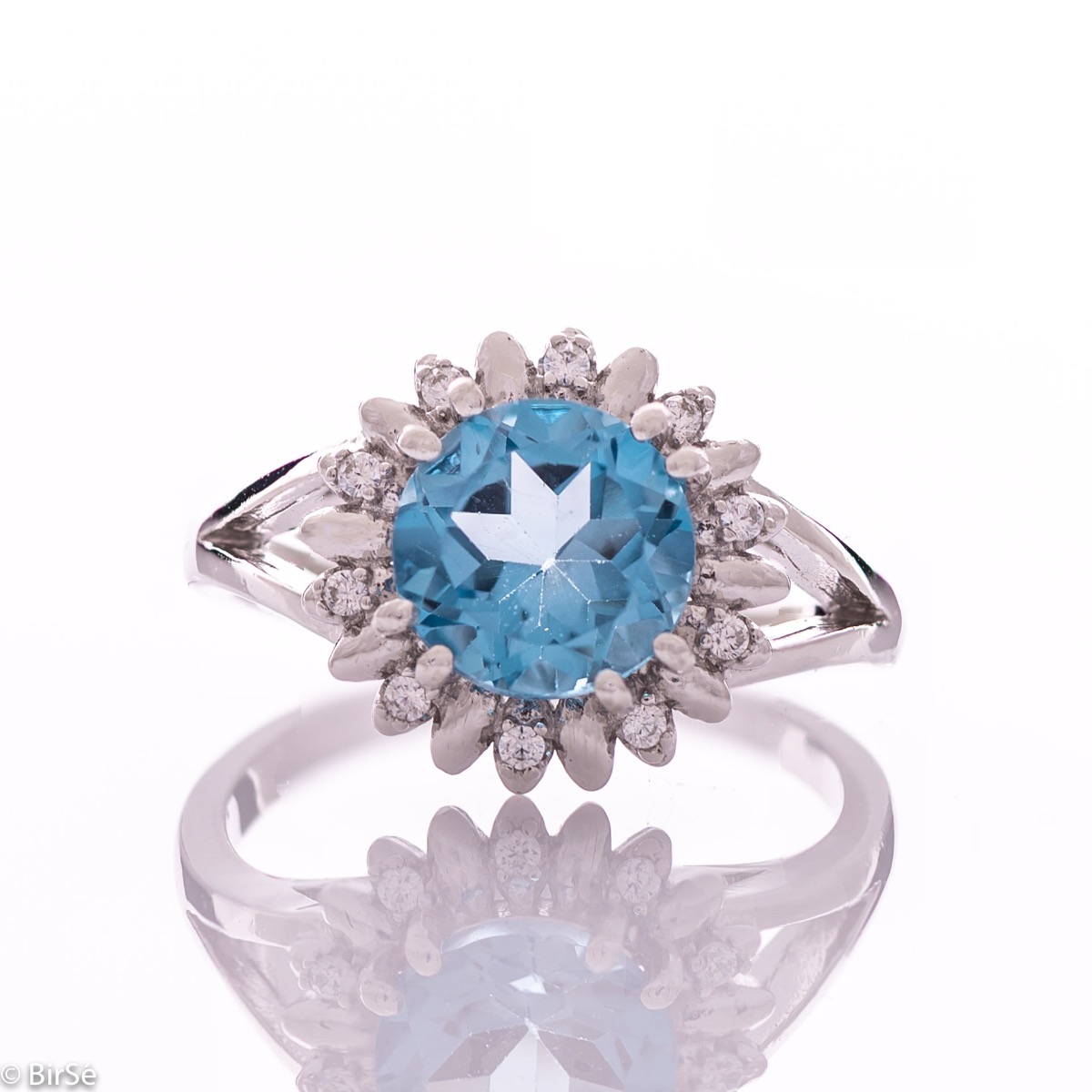 An exquisite women's ring with precise craftsmanship combining delicate rhodium silver with a radiant natural London topaz surrounded by sparkling zircons. Can be combined with earrings and pendant of the same model.