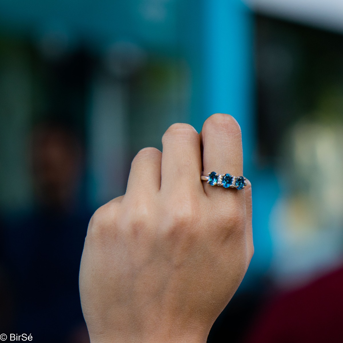 An elegant women's ring with delicate craftsmanship combining rhodium-plated silver with three brilliant natural London topaz stones and sparkling zircons.