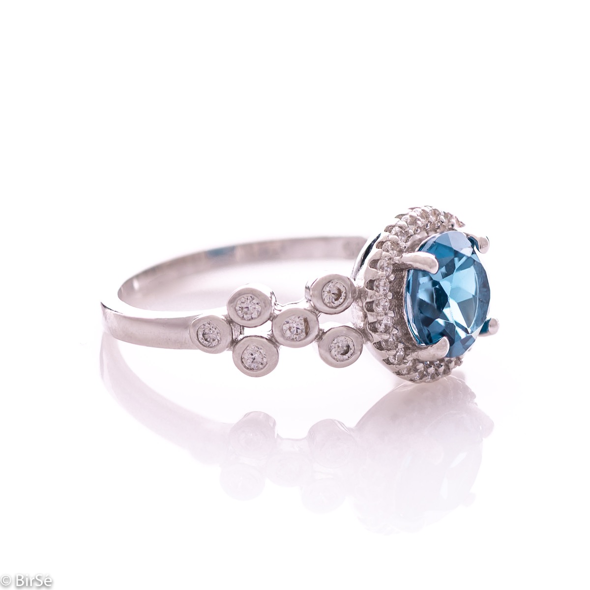 An elegant women's ring with a spectacular craftsmanship entirely of rhodium-plated silver, combined with a radiant natural London topaz and sparkling zircons. Can be combined with earrings and pendant of the same model.