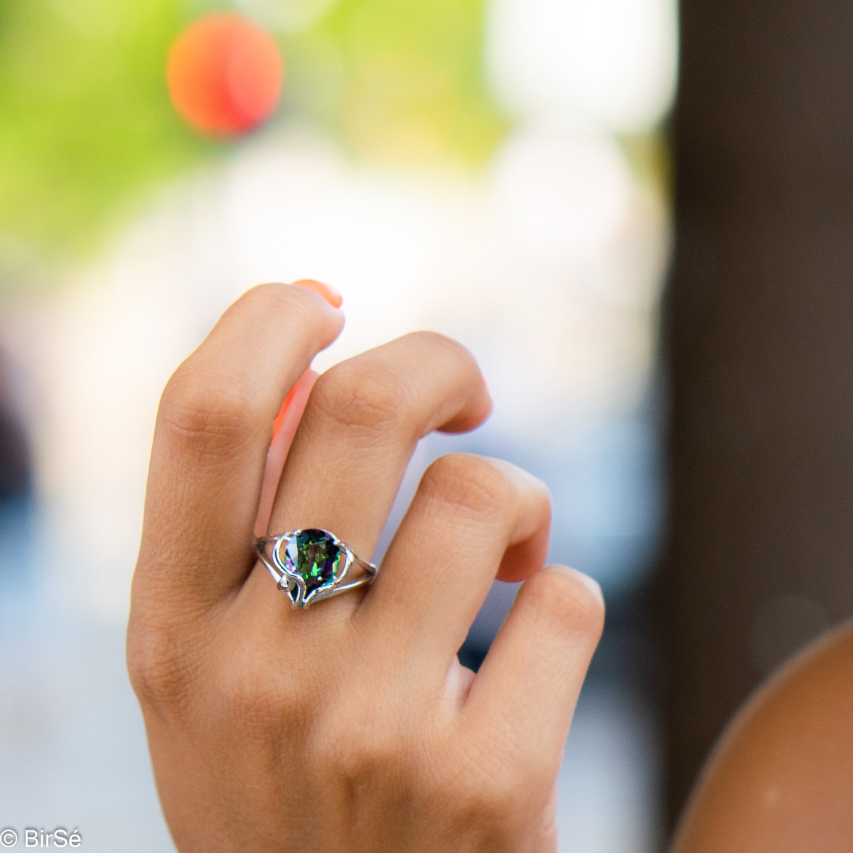 A unique women's ring made of exquisite rhodium-plated silver with gentle curves, intertwining the glow of a natural mystic topaz stone in a beautiful teardrop shape.