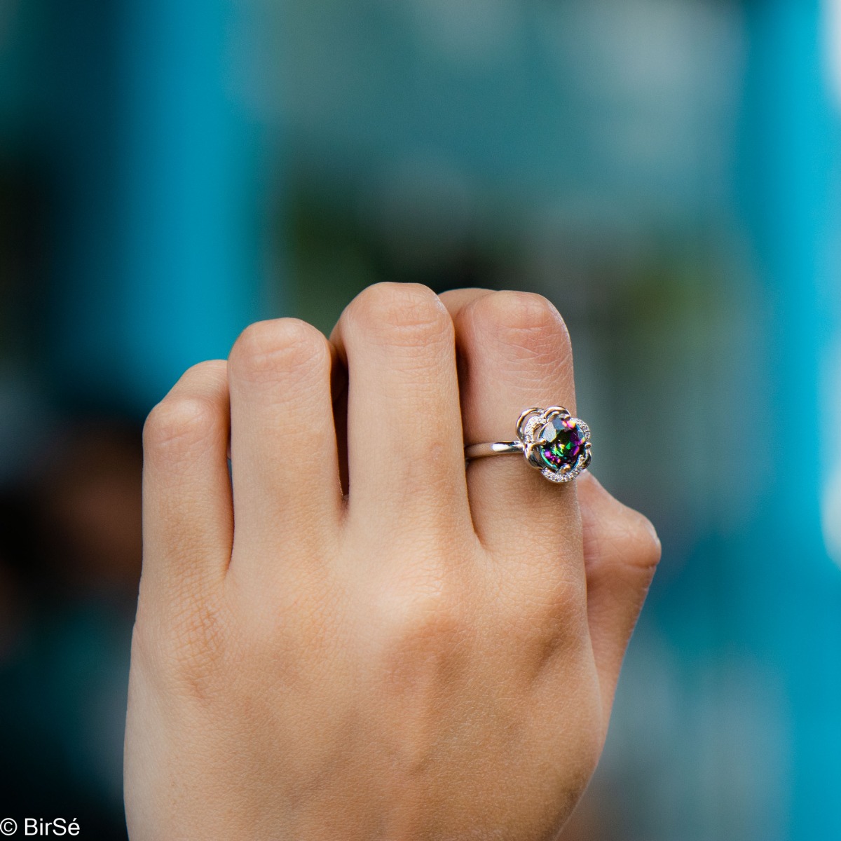 A unique women's ring with precise craftsmanship and delicate curves of rhodium-plated silver, surrounding a sparkling natural stone, mystic topaz and delicate zircons. Part of a charming pendant and earring set.