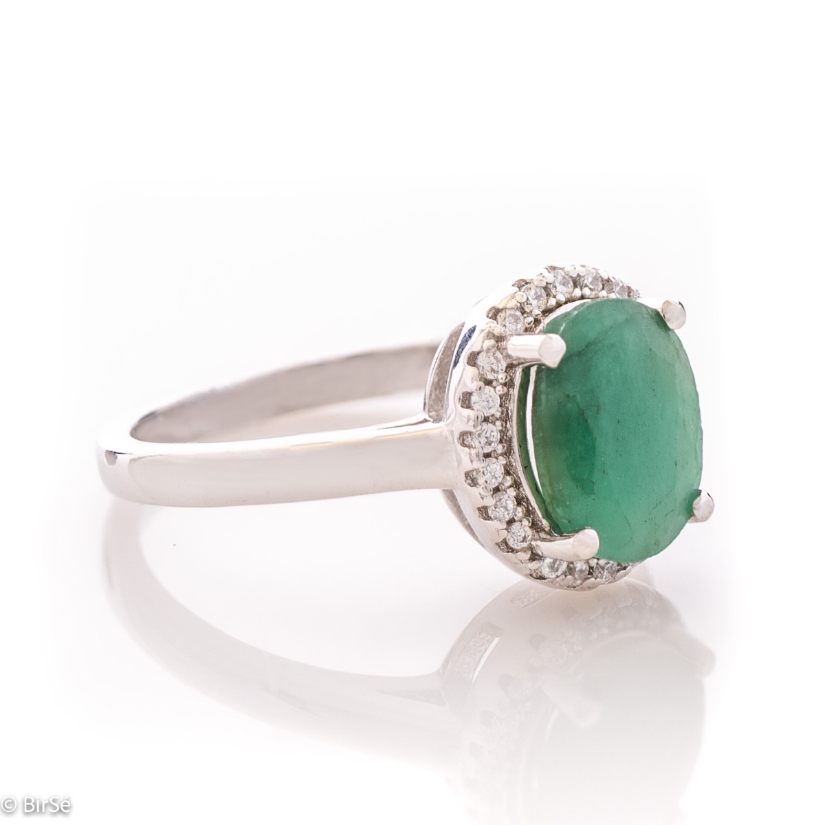 An elegant women's ring with a delicate natural emerald stone, complemented by the sparkle of fine zircons and beautiful craftsmanship entirely in rhodium-plated silver. In a charming set with matching earrings and necklace.