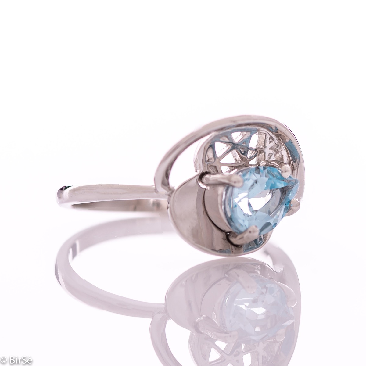 A spectacular women's ring with delicate workmanship entirely of rhodium-plated silver, resembling a heart intertwined with a radiant natural stone blue topaz. It can be combined with a pendant and earrings of the same model.