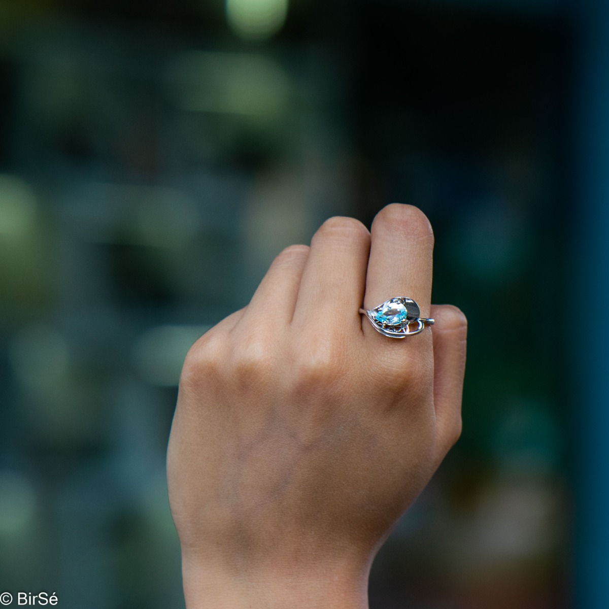 A spectacular women's ring with delicate workmanship entirely of rhodium-plated silver, resembling a heart intertwined with a radiant natural stone blue topaz. It can be combined with a pendant and earrings of the same model.