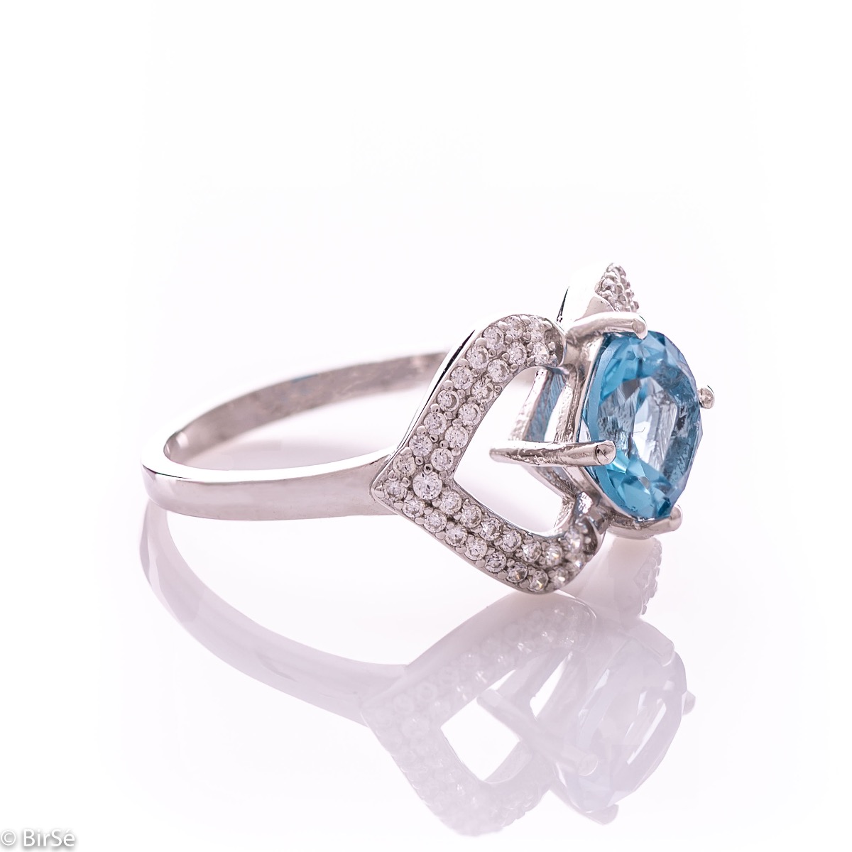 A spectacular women's ring with exquisite workmanship entirely of rhodium-plated silver, combined with a radiant natural stone blue topaz and sparkling zircons. Can be combined with dangling earrings and a pendant of the same model.