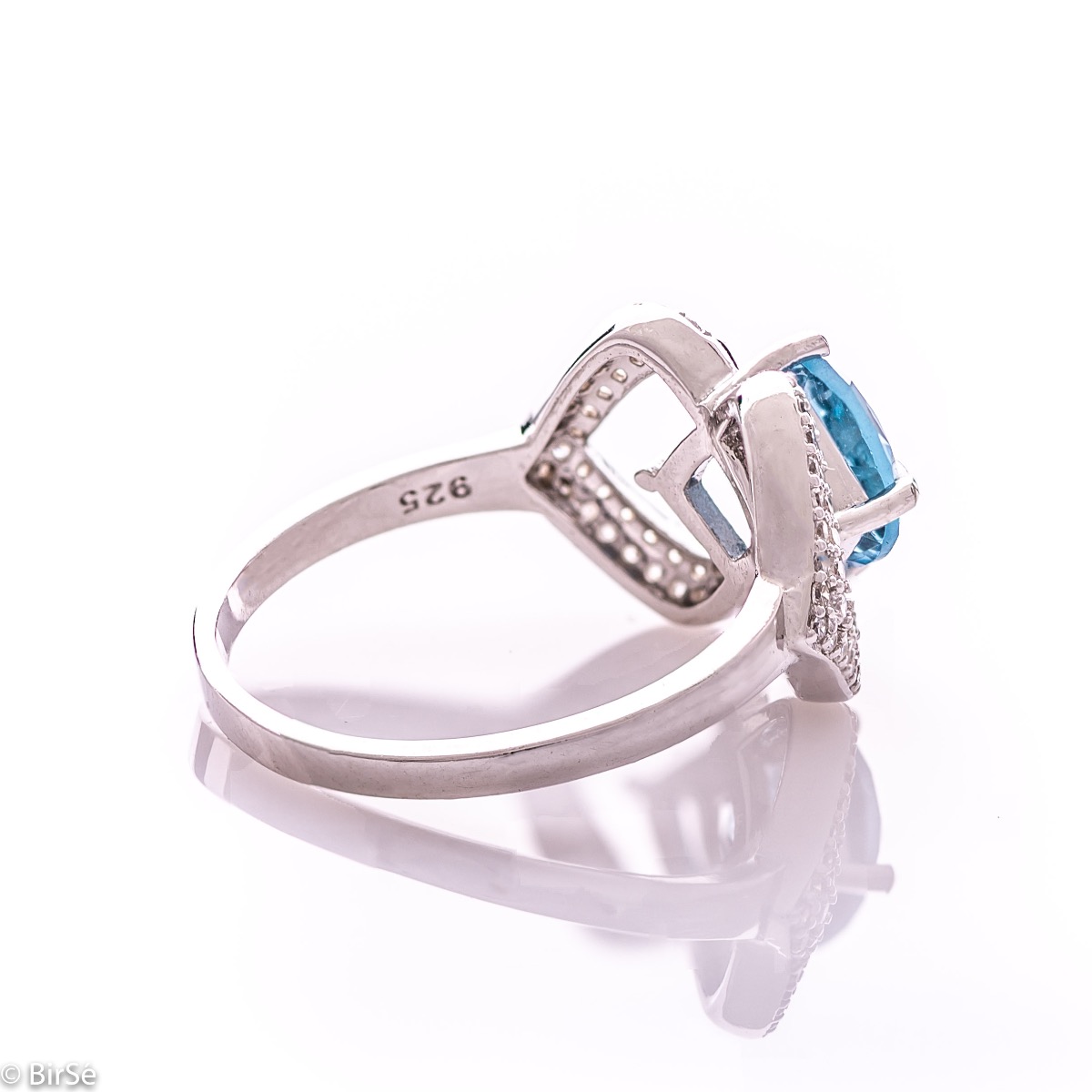 A spectacular women's ring with exquisite workmanship entirely of rhodium-plated silver, combined with a radiant natural stone blue topaz and sparkling zircons. Can be combined with dangling earrings and a pendant of the same model.