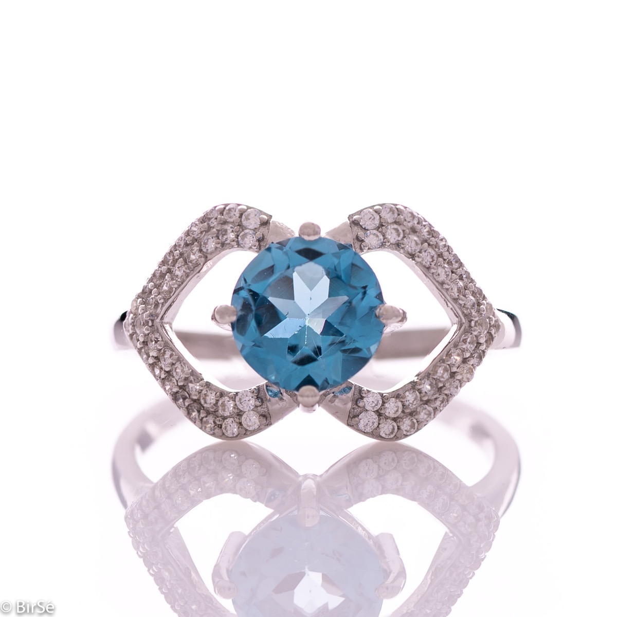 A spectacular women's ring with exquisite workmanship entirely of rhodium-plated silver, combined with a radiant natural stone blue topaz and sparkling zircons. Can be combined with dangling earrings and a pendant of the same model.