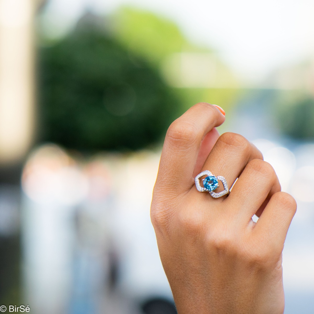 A spectacular women's ring with exquisite workmanship entirely of rhodium-plated silver, combined with a radiant natural stone blue topaz and sparkling zircons. Can be combined with dangling earrings and a pendant of the same model.