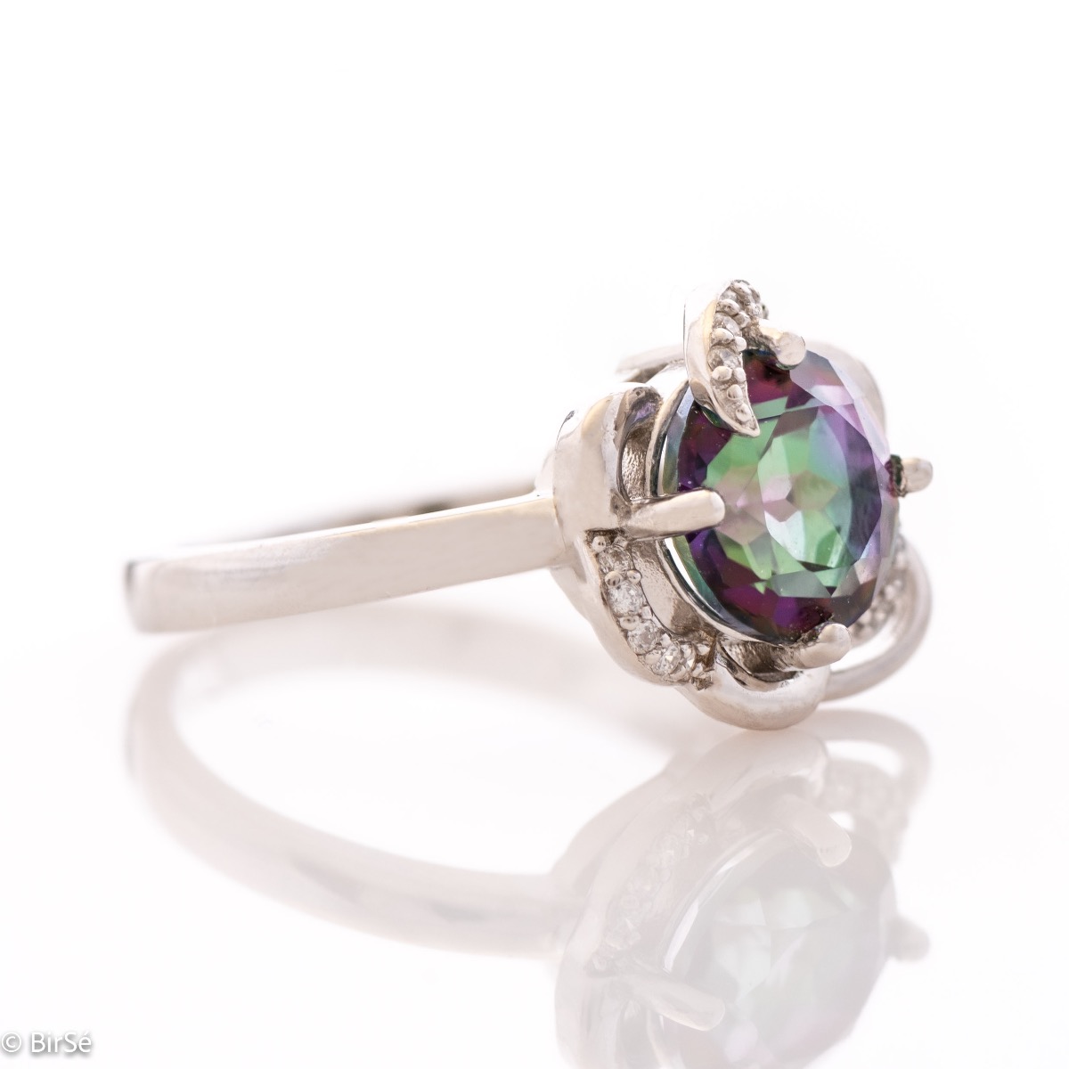 A unique women's ring with precise craftsmanship and delicate curves of rhodium-plated silver, surrounding a sparkling natural stone, mystic topaz and delicate zircons. Part of a charming pendant and earring set.